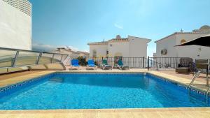 una piscina con sedie blu e una casa di Balcón del Mar a Nerja
