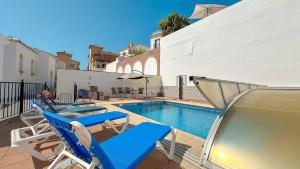 una piscina con sedie a sdraio blu accanto a un edificio di Balcón del Mar a Nerja