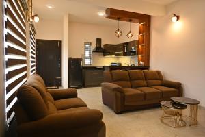 a living room with two couches and a kitchen at Tranquil Touch in Chikmagalūr