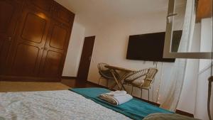 a bedroom with a bed and a chair and a television at Peaceful Boho Room in Costa da Caparica in Costa da Caparica
