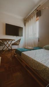 a bedroom with two beds and a table and a television at Peaceful Boho Room in Costa da Caparica in Costa da Caparica