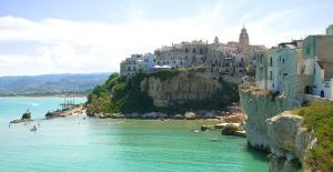 a group of buildings on a hill next to a body of water at Aria di Mare CENTER HOME in Vieste