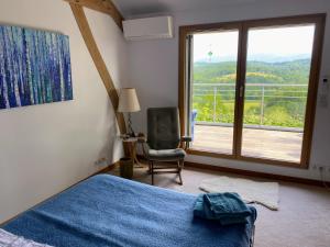 a bedroom with a bed and a chair and a large window at Poulou Pyrénées in Gelos