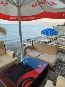 a patio with couches and a table and an umbrella at Guest house Lori in Pogradec