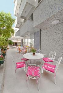 a patio with pink chairs and a white table and chairs at Hotel Tuna in Akçay