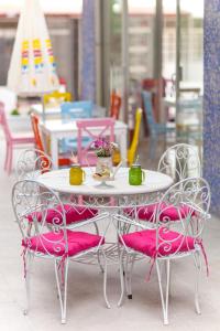 una mesa y sillas blancas con cojines rosas en Hotel Tuna, en Akçay