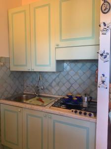 a kitchen with white cabinets and a stove top oven at Ginevra SurfHouse in Palau +15 photos
