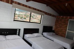 two beds in a room with a window at HOTEL EL PUNTOS sas in Medellín