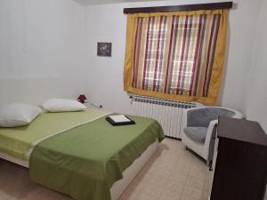 a bedroom with a bed and a chair and a window at Berto in Nerezine