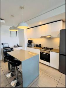 a kitchen with white cabinets and a island with a table at Exclusive Two Bedrooms Presidential Suite in Coral Point in Sibaya