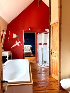 een badkamer met een bad en een rode muur bij Gîte à la ferme in Houplin-Ancoisne