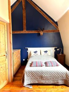 een slaapkamer met een blauwe muur en een bed met kussens bij Gîte à la ferme in Houplin-Ancoisne