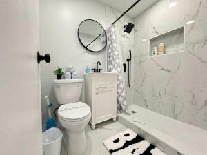 a white bathroom with a toilet and a mirror at Downtown New-Built Roof-top balcony City View 525Pkwy in Atlanta