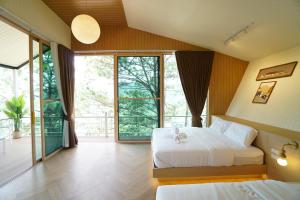 a bedroom with two beds and a large window at บ้านผูกรัก ทะเลหมอก ณ เขาค้อ in Khao Kho