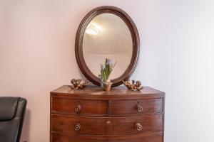 un miroir au-dessus d'une commode avec des fleurs sur elle dans l'établissement Casa Dei Ricci, à Lucques 2 autres photos