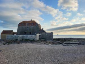 un antiguo edificio en la playa cerca del agua en Aparthotel Des 2 Caps, en Ambleteuse