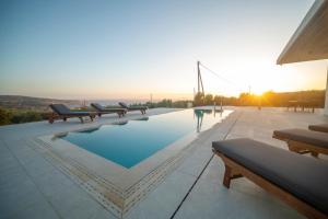 a pool with benches and a sunset in the background at Antiope Retreat in Pitsidia