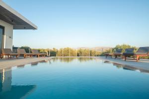 a swimming pool with benches next to a house at Antiope Retreat in Pitsidia