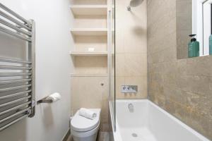 a bathroom with a toilet and a tub and a sink at Modern 2BR Flat with 3 Beds Urban Getaway - Cherry in London +33 photos