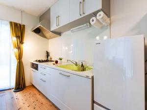 a white kitchen with a sink and a refrigerator at 88kawaramachi 一軒家 in Takamatsu