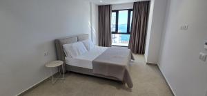 une chambre avec un lit avec des draps blancs et une fenêtre dans l'établissement SeaLuxe Residence, à Saranda
