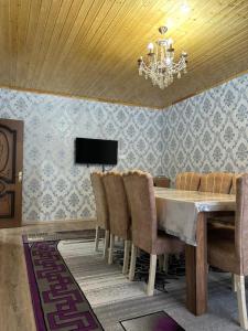 een eetkamer met een tafel, stoelen en een kroonluchter bij Villa Vip in Gabala