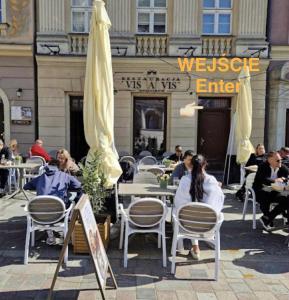 a group of people sitting at tables in front of a restaurant at Apartament VIS a VIS Koziołków in Poznań +3 photos