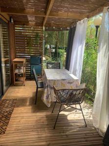 un patio avec une table et des chaises sur une terrasse dans l'établissement Chalet cozy dans Village au cœur des pins, parking gratuit, à Onesse-et-Laharie