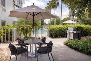 Una mesa con sillas y una sombrilla en un patio. en TownePlace Suites Tampa Westshore/Airport, en Tampa