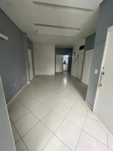 an empty room with white tile floors and a hallway at Spazzio hostel in São José dos Campos