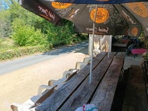 a wooden bench with an umbrella and chairs at tipy 2 in La Celle-sous-Gouzon