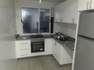 a kitchen with white cabinets and a sink and a refrigerator at ras el ma in Ras El Ma