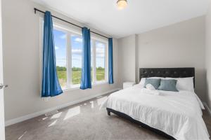 a white bedroom with blue curtains and a bed at Velora Luxe Retreat in Ottawa