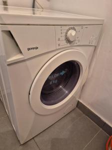 a white washing machine in a corner of a room at Golden View Apartment in Sarajevo