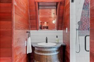 a bathroom with a sink and a wooden wall at Cabernet Wine Barrel Cabin in Fredericksburg