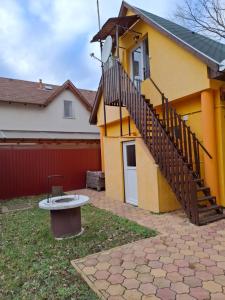 a yellow house with a staircase on the side of it at Fenyves Nyaraló in Hajdúszoboszló