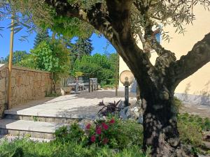 a tree in a garden with flowers next to a sidewalk at Residence Ruje in Prepotto