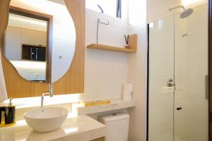 a bathroom with a sink and a mirror and a toilet at ORA Beach Residence by AFT in Porto De Galinhas