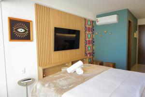 a bedroom with a bed with a tv on a wall at ORA Beach Residence by AFT in Porto De Galinhas