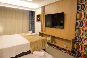 a hotel room with a bed and a flat screen tv at ORA Beach Residence by AFT in Porto De Galinhas
