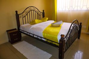 een slaapkamer met een bed met een houten frame en gele lakens bij Kings Square Tebiz Haven in Eldoret