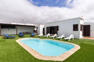 a backyard with a pool and chairs and a house at Villa Car&Melo in Nazaret