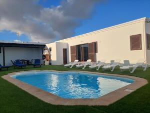 a swimming pool with chairs and a house at Villa Car&Melo in Nazaret