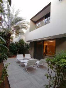 a patio with white chairs and a table and a building at Vivienda Hada Residences in Riyadh