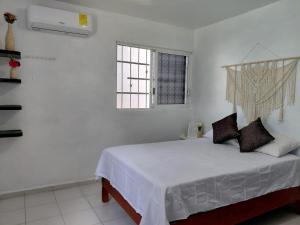 a white bedroom with a bed and a window at Casa Marlix in Acapulco