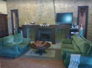 ein Wohnzimmer mit 2 grünen Stühlen und einem Kamin in der Unterkunft Casa Cortijo in La Luisiana