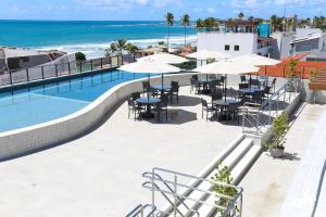 a pool with tables and umbrellas next to the ocean at ORA Beach Residence by AFT in Porto De Galinhas