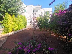 a garden in front of a white building with purple flowers at Villette Mar Ionio in Nardò