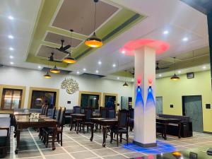a dining room with tables and chairs and a column at Kanha Hotel and Restaurant in Jāmb