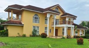 a large yellow house with a large yard at Zoey Casa in Accra